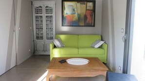 A living room with a green sofa, a wooden coffee table, and a painting on the wall. - Charming house close to the sea and cycle paths (Saint-Martin-de-Ré)