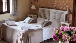 Ein Schlafzimmer mit Steinsturz, einem Bett mit Kopfteil, einem Nachttisch mit Lampe und einer Vase mit Blumen auf einem Tisch.