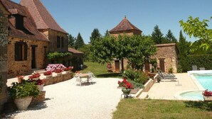 Ein Innenhof mit Pool, Steinbauten und Außenbestuhlung.