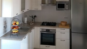 Eine moderne Küche mit weißen Schränken, einem Edelstahlkühlschrank, einer Mikrowelle und einem Gasherd.