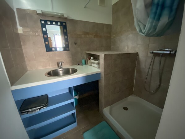 A bathroom with a sink, mirror, and shower. - 2-bedroom villa in a quiet garden with trees and flowers (Le Diamant)