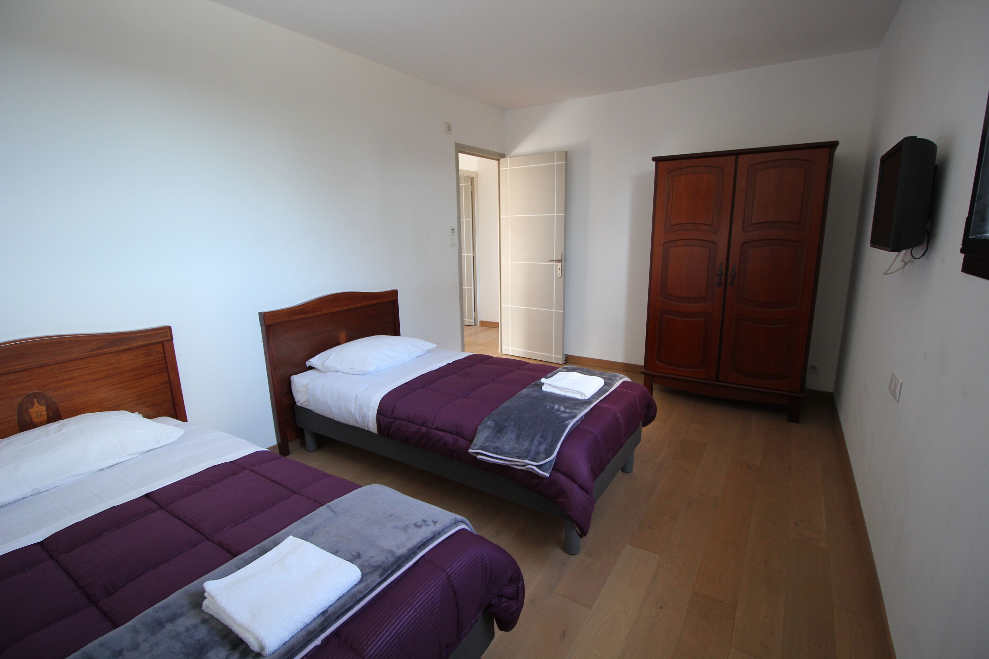 A room with two beds, a wardrobe, and a television.