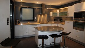 Una cocina moderna con una isla central, electrodomésticos de acero inoxidable y taburetes de bar.