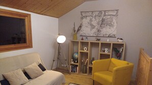 Ett mysigt vardagsrum med en soffa, en gul fåtölj, en jordglob på en hylla och en karta på väggen.