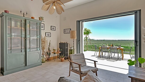 A spacious living area with a large window, a dining table, and a green cabinet. - La Maison des Vendangeurs***, Gîte with swimming pool and bicycles  (Beaucaire)