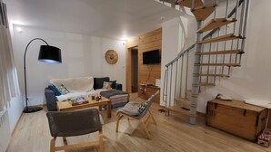 A living room with a sofa, coffee table, and chairs, a staircase, and a wooden chest of drawers. - Charmante maison au coeur du village /Charming house in the heart of the village (Wissant)