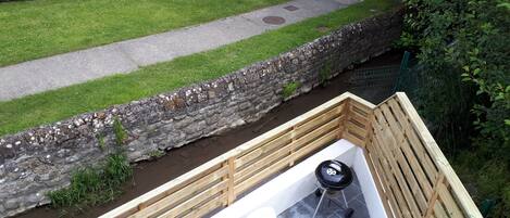A patio area with a stone retaining wall, a wooden deck, and a white outdoor table and chairs.