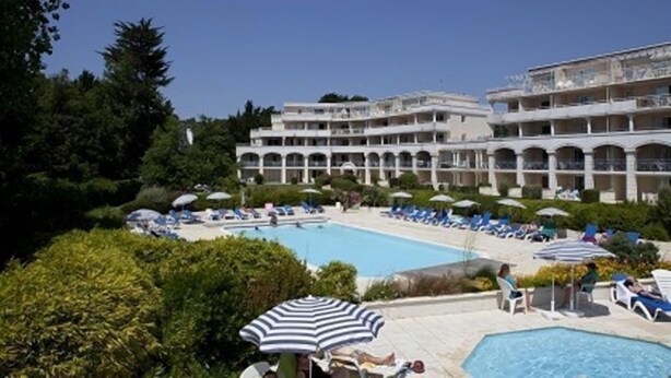 Et hotel med swimmingpool, liggestole og parasoller.