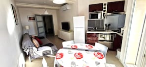 A compact living space with a kitchenette, a dining area, and a sofa with a TV. - 2-room air-conditioned apartment. Sea and harbour view, quiet town centre (Bandol)