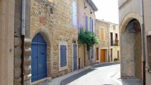A narrow street lined with stone buildings, featuring arched doorways and a mix of blue and yellow doors.