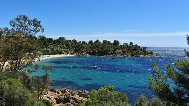 A coastal landscape with a beach, clear blue sea, and dense greenery. - Charming sea view villa quiet close to the beaches (Le Lavandou)