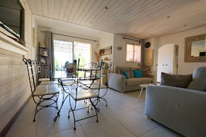 Un salon avec un canapé, une table à manger et des chaises, une fenêtre et une porte.
