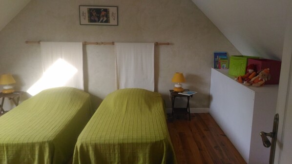 A room with two single beds, a small table with a lamp, a shelf with toys, and a framed picture on the wall. - House, The sea field Plouha (Plouha)