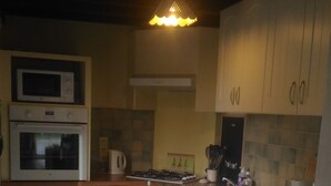 A compact kitchen with white cabinets, a microwave, an oven, a sink, and a coffee maker. - House, The sea field Plouha (Plouha)
