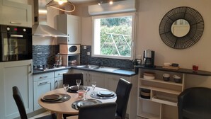 A modern kitchen with a dining area, featuring a built-in oven, microwave, and sink. - Recently built house, nice setting, 500 m from sea, at heart of pedestrian hill (Tréveneuc)