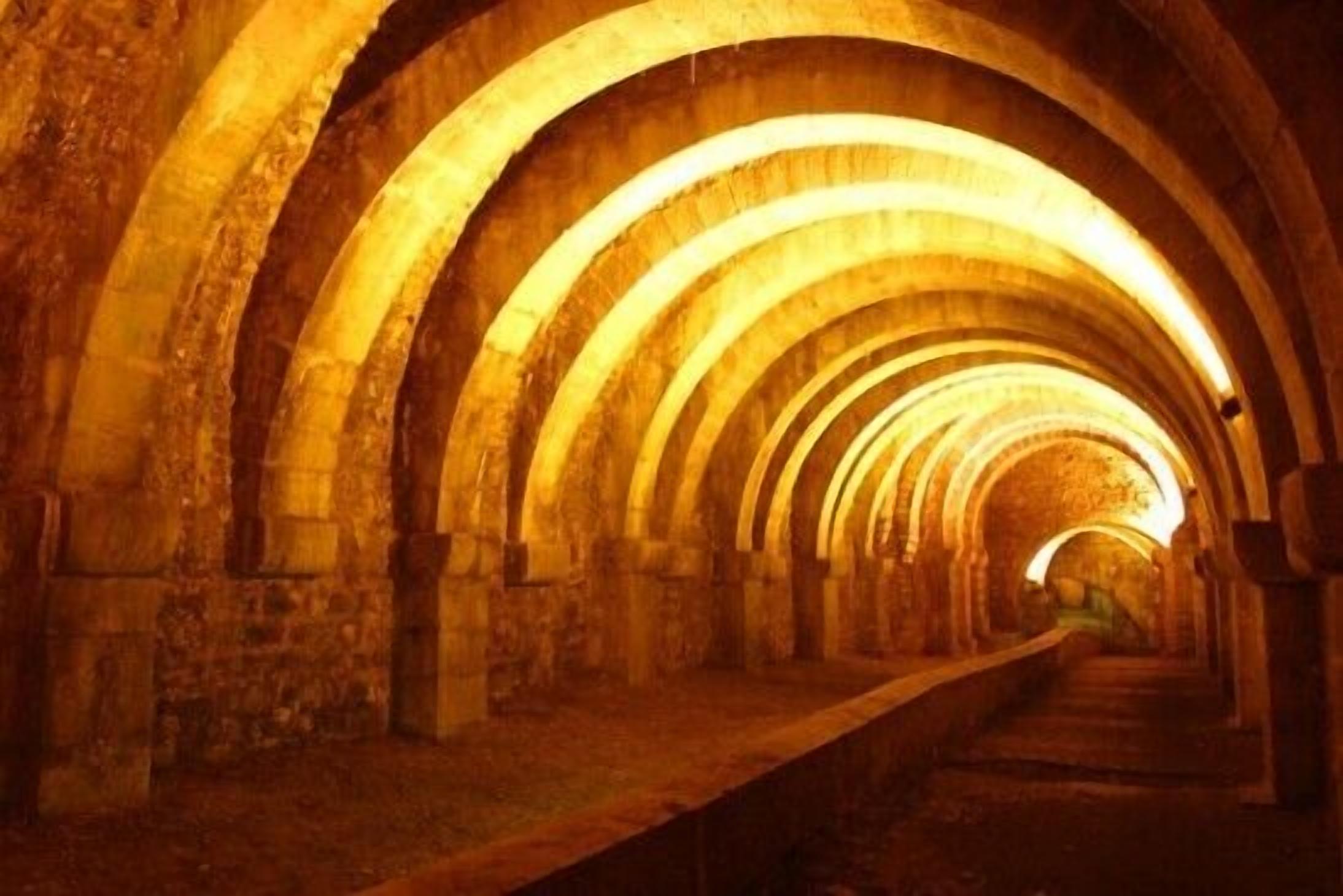 Un couloir en pierre, doté d’arches et d’une allée centrale.