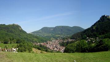 A rural village nestled in a valley with a prominent hill and a castle-like structure on top.