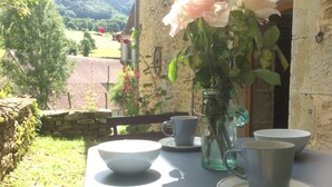 A table with a vase of roses and several cups and saucers.