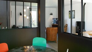 En moderne stue med et glasbord, en grøn lænestol og en fletstol.