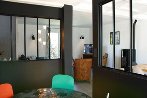 Ein modernes Wohnzimmer mit Glastisch, grünem Sessel und Korbstuhl.