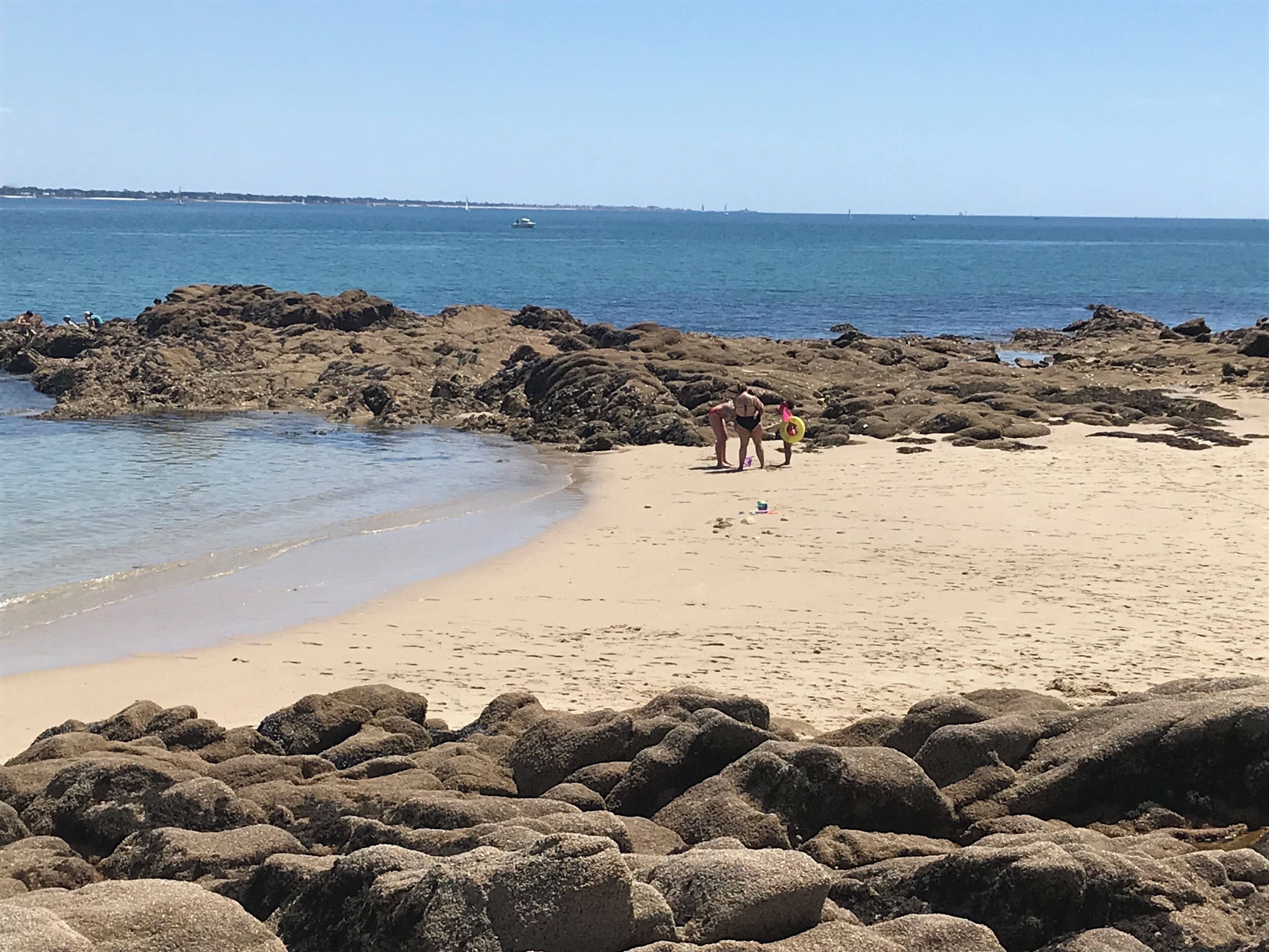A rocky beach with clear water and a distant shoreline.