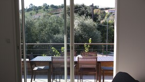 Un balcon avec une table et des chaises, donnant sur un jardin et des immeubles.