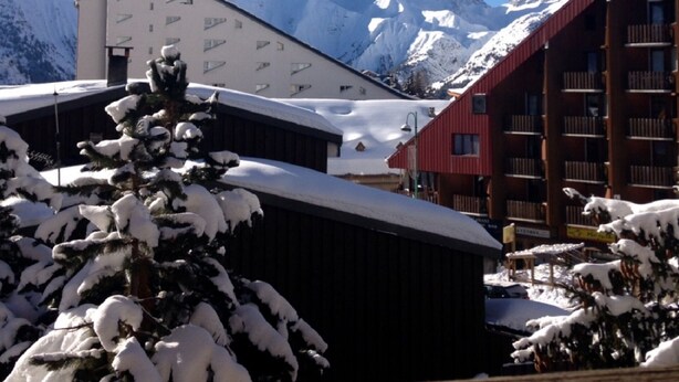 Um edifício com telhado inclinado, rodeado por montanhas cobertas de neve.