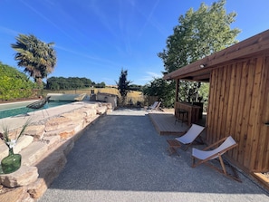 Uima-allasalue, jossa on aurinkotuoleja, puinen terassi ja pergola.