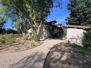 A stone building with a red-tiled roof, surrounded by trees and a gravel path. - Stone house for 6 people, heated pool, bowling green, summer kitchen  (Bertric-Burée)
