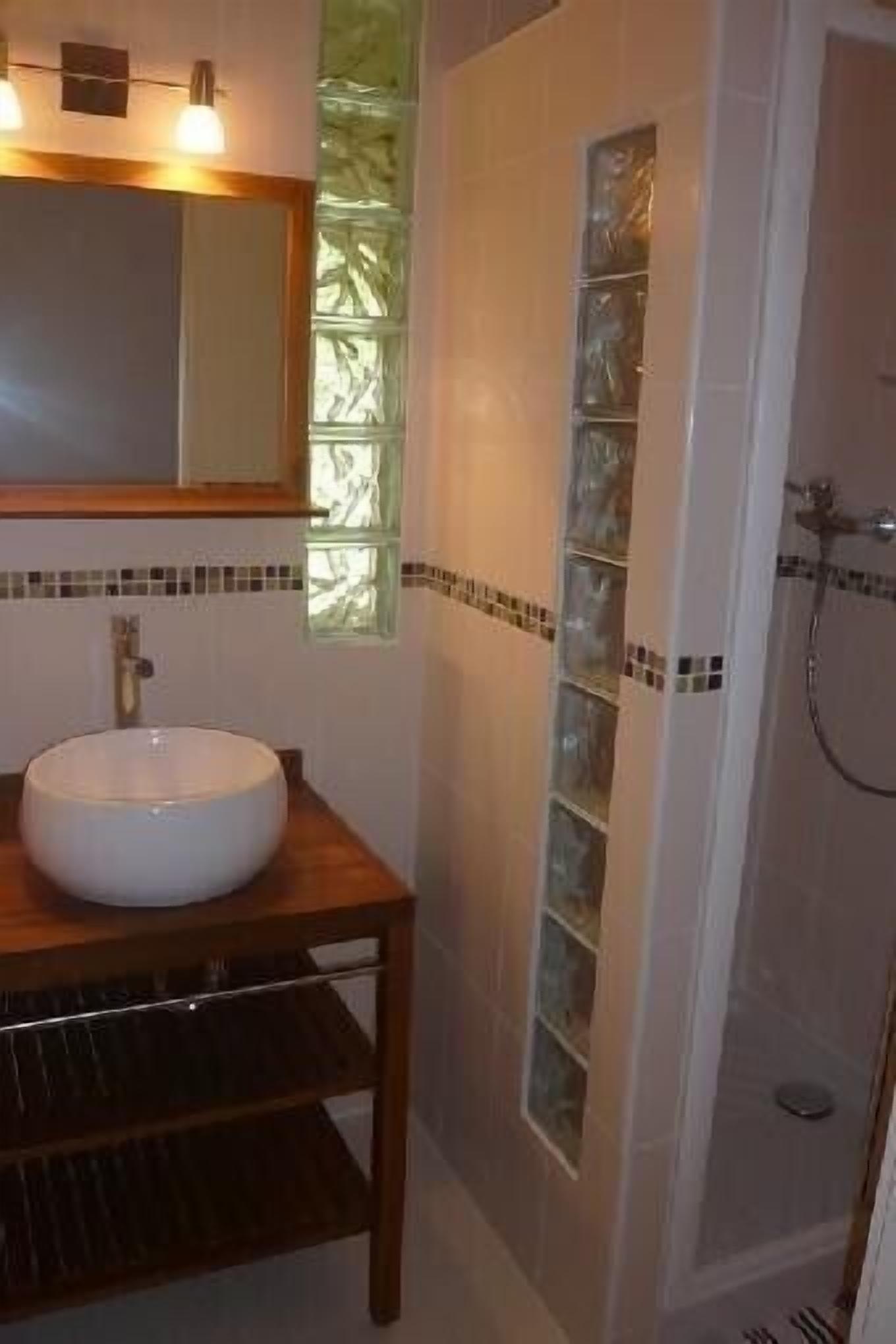 A bathroom with a wooden vanity, a white sink, a mirror, and a glass shower enclosure.