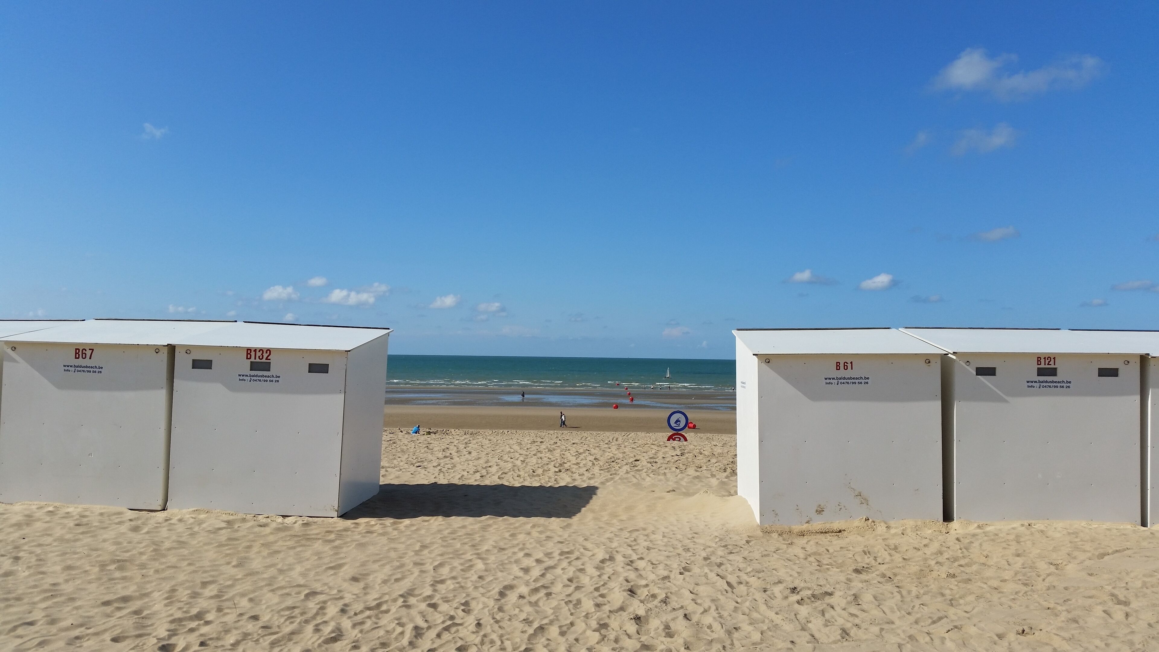 Una playa con dos cabañas de playa blancas identificadas con las etiquetas B67 y B132, y B61 y B121.