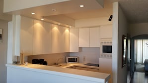 A modern kitchen with white cabinets, a microwave, and a sink.