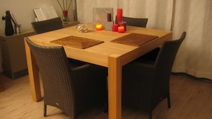 A dining table with four chairs, candles, and a vase with flowers.