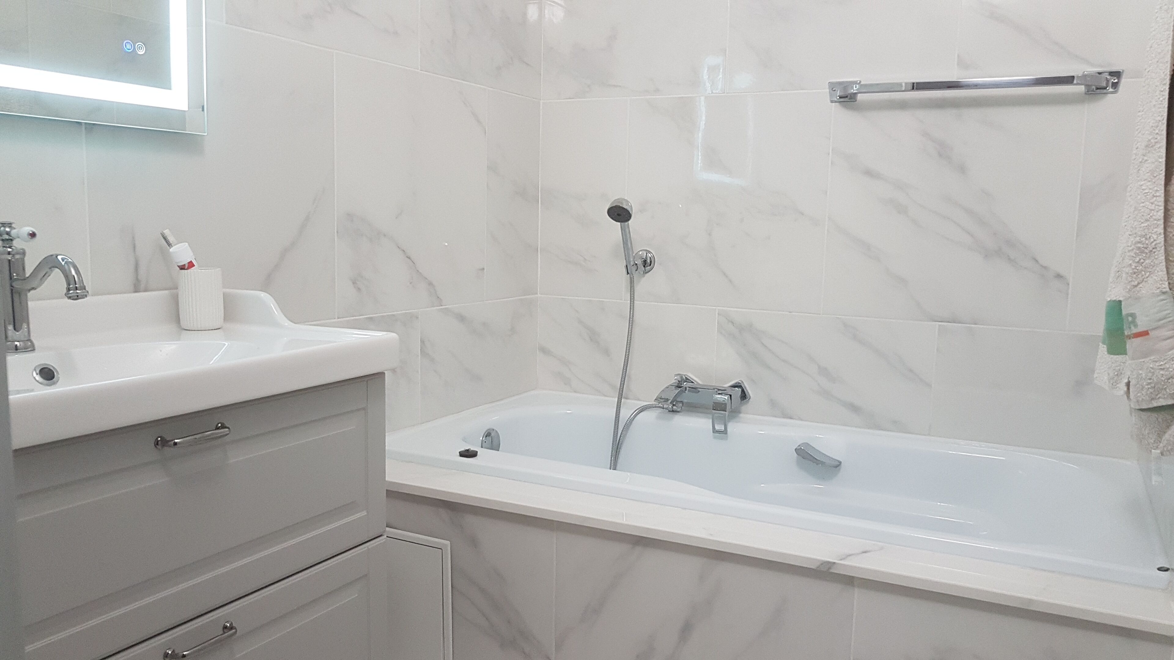 A bathroom with a white sink, mirror, and bathtub.