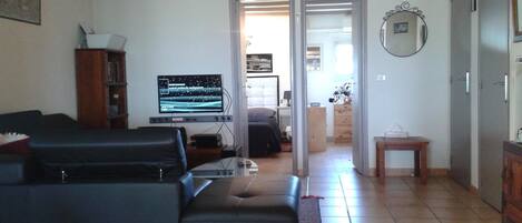 Una sala de estar con un sofá negro, un televisor de pantalla plana y un mueble de madera.