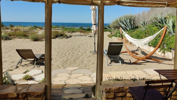 Une terrasse au bord de la plage, avec deux chaises longues, un hamac et une vue sur l’océan.