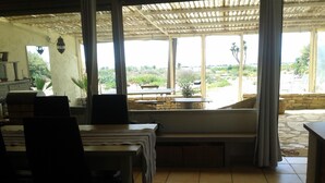 Un espace extérieur abrité où l’on peut prendre ses repas, avec vue sur un jardin et un mur en pierre.