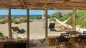 Un espace extérieur abrité, aménagé avec des sièges, et offrant une vue sur la plage et l’océan.