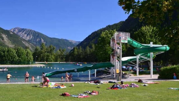 A water park with a water slide and a pool surrounded by mountains.