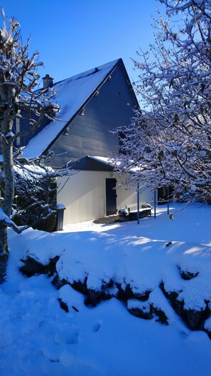 A house with a sloped roof, a small attached garage, and a snow-covered yard. - GÎTE 3 STARS, BESSE & ST-ANASTAISE, Theme: SKIING, HIKING, VISITS, FISHING (Besse-Et-Saint-Anastaise)
