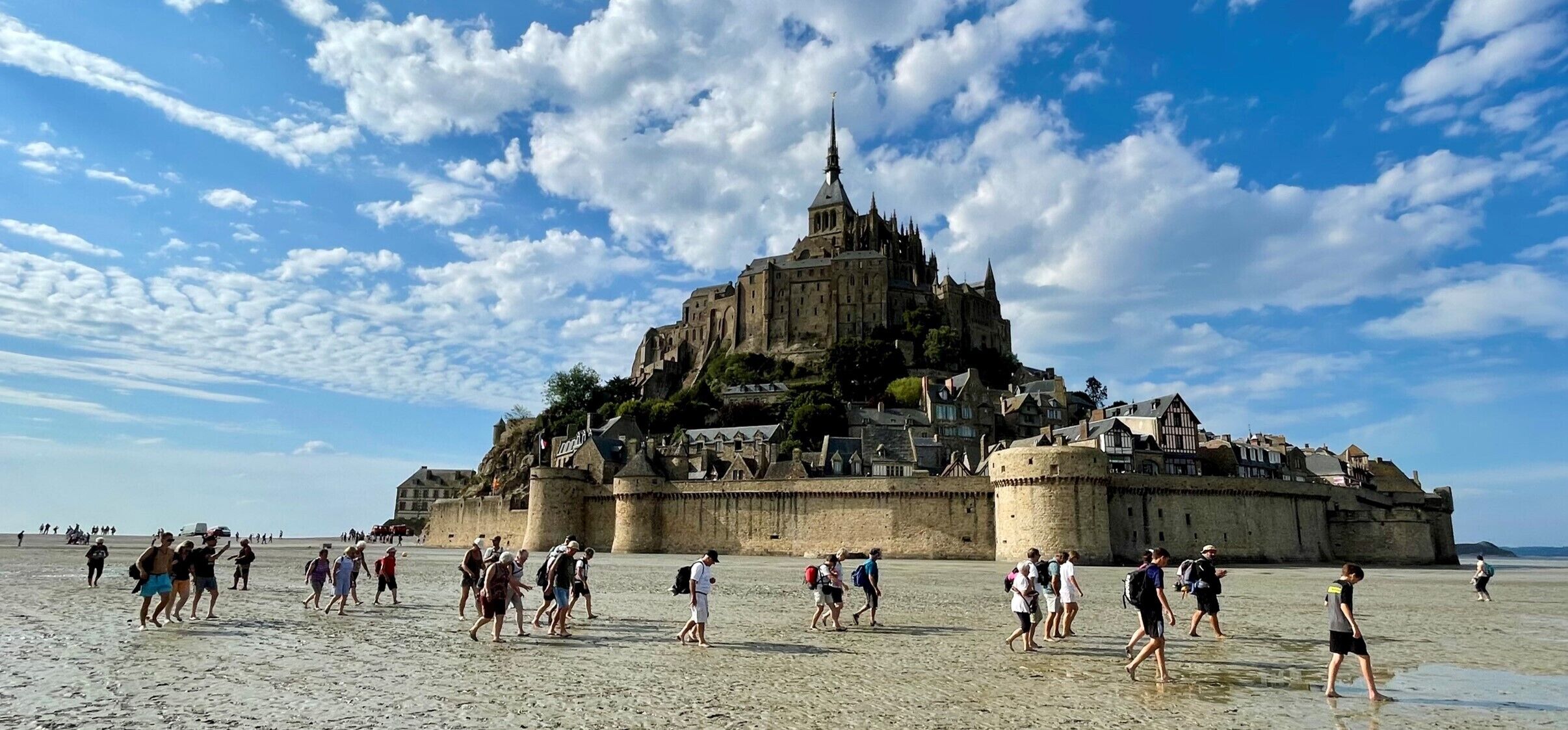 Un castillo histórico en la playa con turistas caminando.