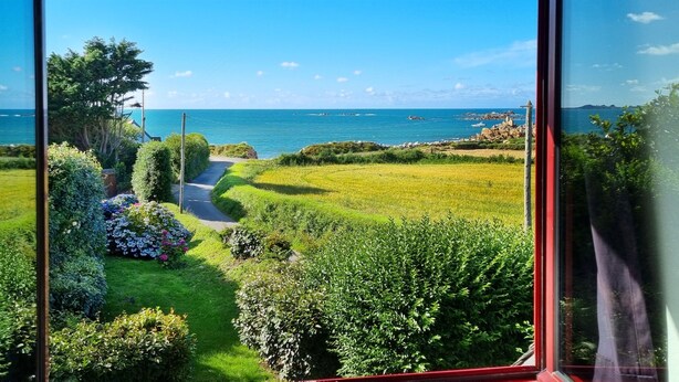 A view of a coastal landscape with a grassy area, a pathway, and a body of water.