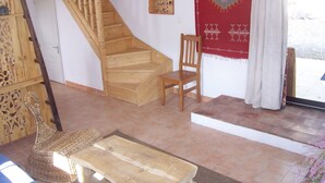 A wooden staircase, a wooden chair, a woven bench, and a red patterned wall hanging. - Brand new gite in an authentic Provencal Mas, in south Ventoux (Méthamis)