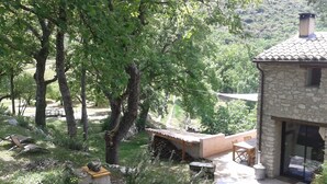 A stone house with a tiled roof, surrounded by trees and a patio area with outdoor furniture. - Brand new gite in an authentic Provencal Mas, in south Ventoux (Méthamis)