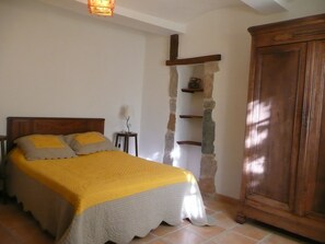 Un dormitorio con cama, mesita de noche, lámpara, estante de piedra y armario.