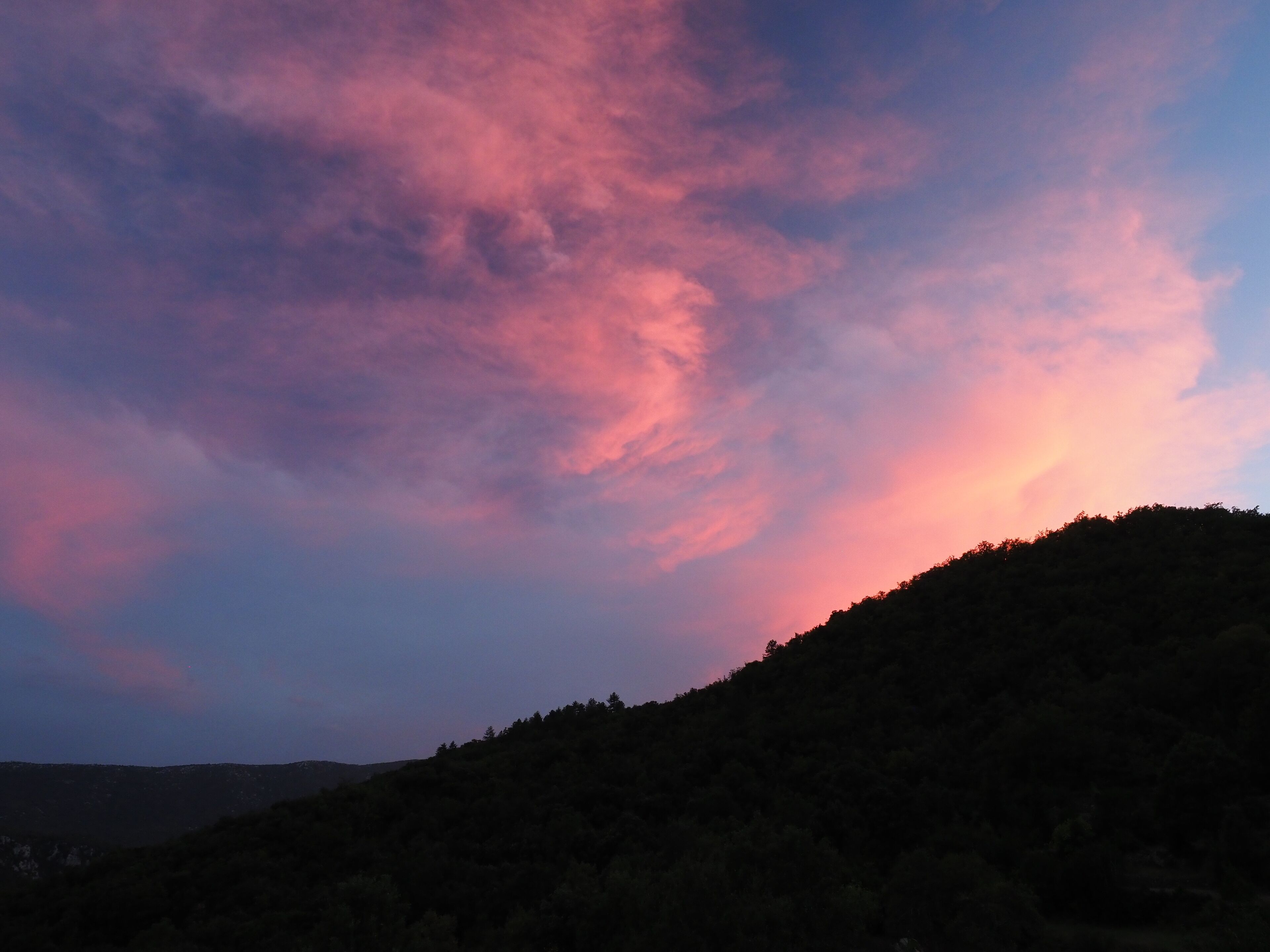 A sunset over a hilly landscape with a clear sky.