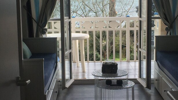 Een kamer met balkon, een tafeltje en een bank.