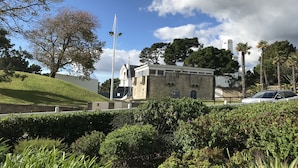 Een historisch gebouw met een stenen gevel, omringd door weelderige begroeiing en een heldere lucht.