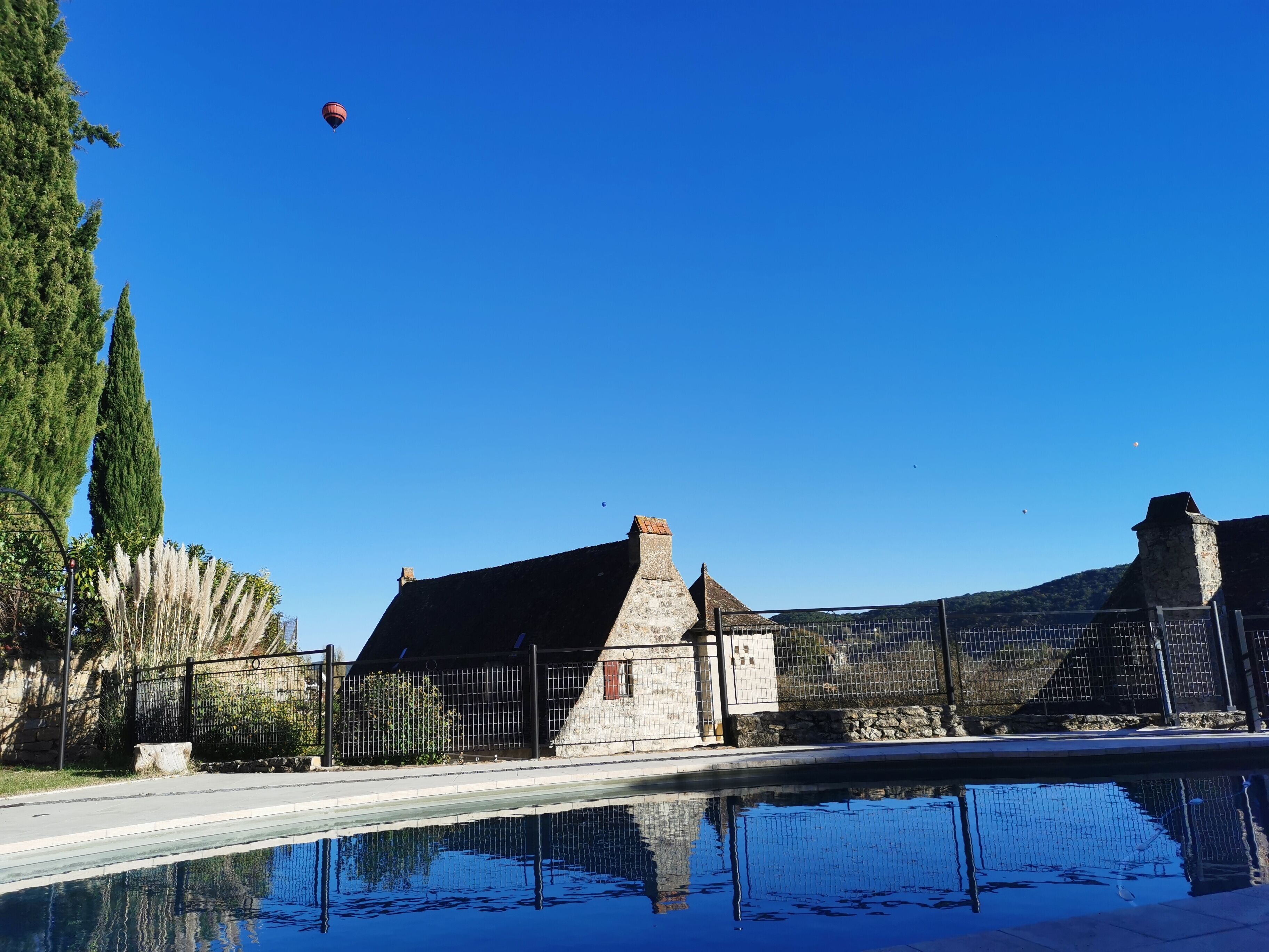Un cielo azul claro, una piscina y un edificio de piedra con una cerca.