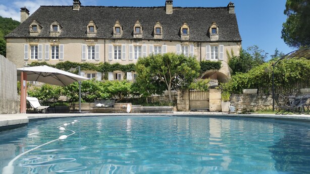 A swimming pool with a stone building in the background. - Authentic Périgourdine house comfort & calm (Beynac-Et-Cazenac)